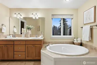 Primary bedroom en-suite bathroom with soaking tub and walk-in shower, double-sink vanity and window brings in extra light.