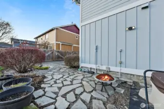 stone pavers lead from driveway patio to the hot tub around side of house from garage in backyard.
