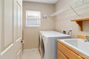 Laundry room has a sink, cabinetry, folding counter, shelving and another closet.