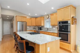 Stunning kitchen with wall oven, cooktop on functional island and hardwood floors.