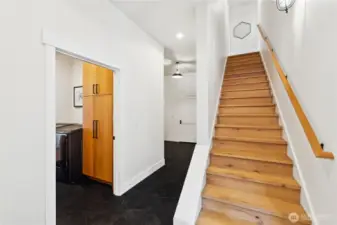 Hallway with hexagon tiles off kitchen leads to utility room, mudroom off the garage and stairway to giant family multi-purpose bunk room.