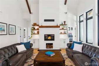 Living room with shiplap fireplace surround, wood burning fireplace and wood box. Built in cabinetry and shelving flank the fireplace - perfect for storage!