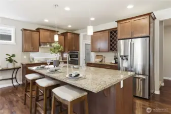 Additional kitchen view showcasing the full suite of stainless-steel appliances and the conveniently placed walk-in pantry in the hallway to the garage