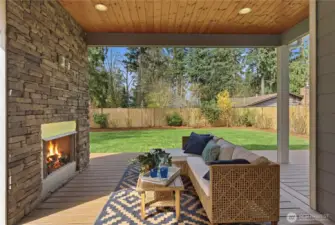 A welcoming covered patio designed for all-season living, complete with a built-in gas fireplace and TV hookup, durable Trex-style decking, and a natural-gas line for effortless grilling
