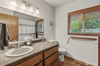 Main floor bath with vinyl floors, oak cabinets, new lighting fixtures and nice window treatments.