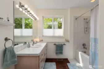 Full bath with tiles tub and shower surround and roomy vanity.