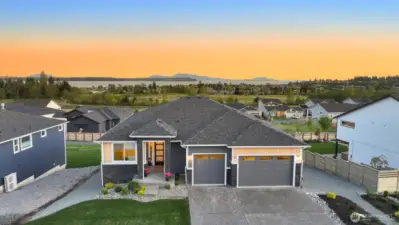 Beautiful front exterior with well-maintained landscaping and welcome entry set against a stunning sunset backdrop.