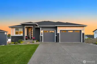 Attractive curb appeal featuring spacious driveway, covered entry and landscaped front yard with sunset views.