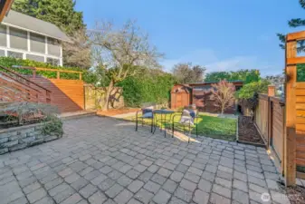 Patio area and terraced backyard with 2 outbuildings