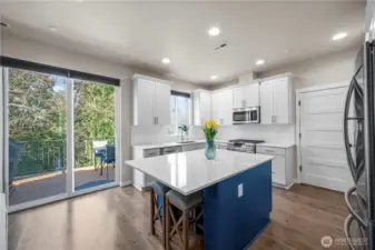 Designer kitchen with quartz counters, tile backsplash, and stainless appliances.