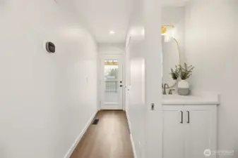 You don't appreciate it until you experience it. The main-level, fully remodeled powder bath is set away from the living room and kitchen. At the end of the hall is the new custom door leading to the deck and yard. Behind here is the door to the big garage.