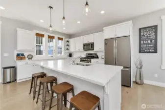 Kitchen with quartz countertops, stainless steel appliances and a sit up bar.