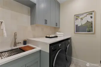 Spacious separate laundry room with ample built in storage, countertop space, and a deep utility sink.