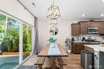 Formal dining room with elegant lighting and large windows showcasing backyard views.