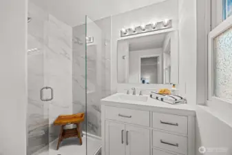 This primary bathroom has no expense spared! High end tilework, custom glass shower doors, a brand new vanity and lighting!