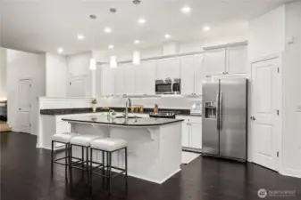 The gourmet kitchen features granite countertops, a statement island, & rich repainted cherry cabinetry