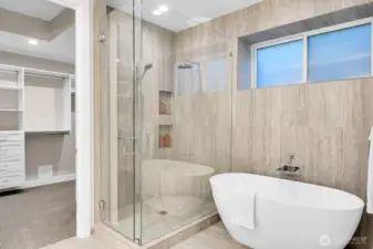 Lower level primary soaking tub and floor to ciling tiled shower w/ bench, private toilet room and extra linen storage closet.