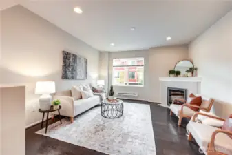 Living room with tall ceilings, engineered hardwood flooring & a fireplace.