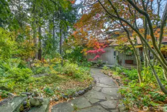 Pathway to front porch and lower level meanders through this lush, fenced in garden  with a mix of native, annual, perennial, deciduous and evergreens create patterns, texture and color all year.