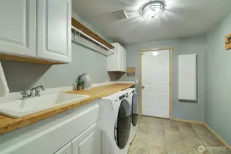 Super functional laundry room, with cabinets, sink, folding counter, hanging rack and in the wall ironing board.