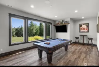 Expansive lower-level space with room for a pool table, surrounded by oversized windows that bring in natural light and overlook the picturesque backyard and rolling territorial views.