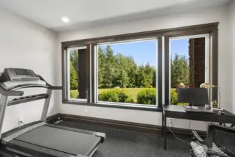 Thoughtfully designed home gym with premium rubber flooring and a statement window capturing serene backyard and wooded views. This bright, energizing space blends performance and tranquility — bringing the outdoors in while supporting your active lifestyle.