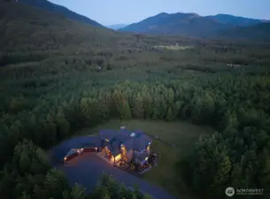 A breathtaking aerial view of this private 10-acre Ravensdale estate, surrounded by lush evergreens and rolling foothills. Tucked into nature with expansive territorial views, this custom home offers rare seclusion, usable land, and endless possibilities for equestrian amenities, a shop, pool, or future expansion. A true Pacific Northwest retreat.