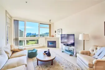 Stunning Seattle skyline views from living room featuring gas fireplace and access to deck.