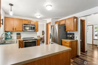 View of the kitchen from the family room, love all the counter space and included stainless steel appliances. Powder room down the hall to your right on the left.
