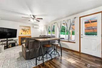 View from the kitchen to the family room, so much to love! Large room, huge windows, ceiling fan, Ductless Mini Split and fireplace for year-round comfort.