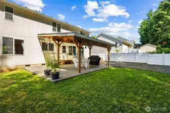 Backyard view of home and covered patio, fully-fenced and easy to maintain.