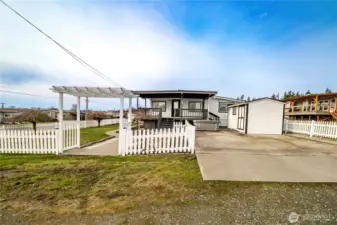 Welcome to 8471 Willow Way primary driveway entry iew with covered viewing deck/porch, hot tub and garden shed