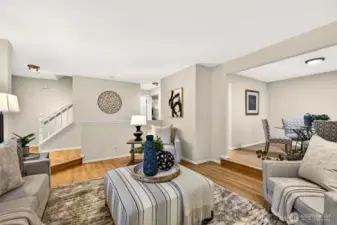 The living room's generous layout and open connection to both the entry and dining area create a natural gathering space where the flow of the home truly shines — hardwood floors, fresh paint, and abundant natural light make this a space that feels both polished and livable.