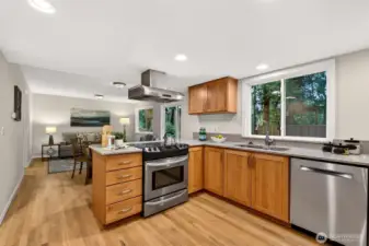The thoughtfully designed kitchen opens directly to the main living areas, offering stainless steel appliances, warm cabinetry, quartz countertops, and new recessed lighting — a setup that makes everyday cooking and casual entertaining equally effortless.