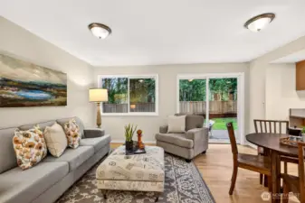 This comfortable lower level gathering space flows naturally toward the backyard patio through a sliding glass door, with refinished hardwood floors, fresh paint, and a serene wooded backdrop creating a relaxed and welcoming atmosphere.