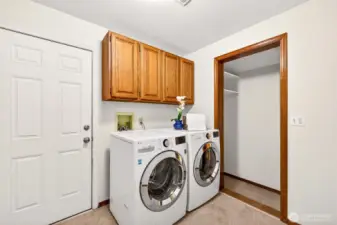 A dedicated main level laundry room with full size LG washer and dryer, overhead cabinetry for storage, and extra shelving in the adjacent hallway add exceptional everyday convenience — a feature that makes a real difference in how smoothly this home lives.