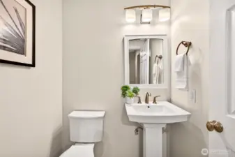 The convenient main level half bath is tastefully appointed with a pedestal sink, brushed gold fixtures, heated floors, and updated lighting — a polished detail that makes a strong impression on guests without sacrificing an inch of practicality.