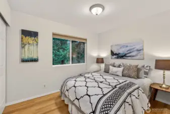 This well-proportioned upper level bedroom with hardwood floors and a serene view of the surrounding evergreens provides a calm, inviting space — equally suited for a guest room, home office, or personal sanctuary.