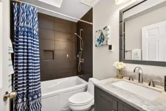 The remodeled full hall bath is a genuine showstopper, featuring bold large format tile surround, a soaking tub and shower, marble countertop, heated floors, and refined fixtures — a complete renovation that serves the upper level bedrooms with style and comfort in equal measure.