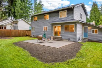 The rear of the home reveals a well-proportioned two-story footprint with direct patio access from the main level, abundant windows that bring natural light deep into the interior, and a generous lawn that makes the most of every square foot of the 8,750 SF lot.