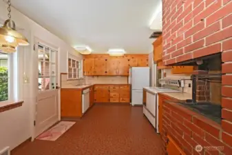 Kitchen is off the Dining Room. Ample eating area and access to the patio and backyard. Note the classic pine cabinets and an indoor grill with its own chimney.