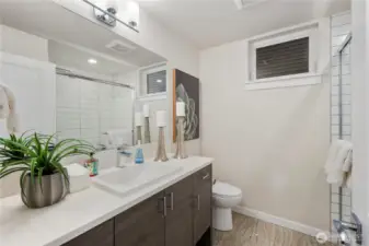 Main level bathroom features large walk in tiled shower, tiled floors, quartz-topped contemporary cabinetry and natural light.  Grohe fixtures.