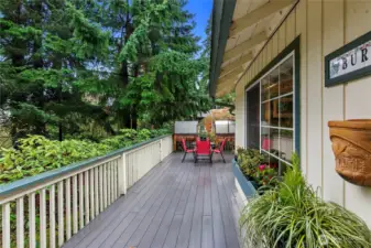 Large deck off of the front of the house with 2 green house units at the end.