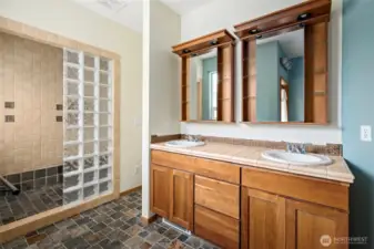 Primary bath features a double sink and full glass block shower.