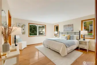 Spacious and serene primary suite with hardwood floors, large windows, and peaceful treetop views. Natural light fills the room, creating a relaxing retreat.