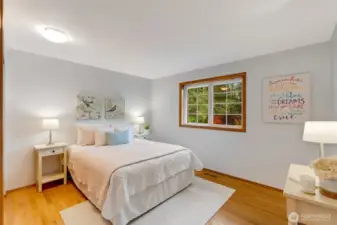 Bright and tranquil bedroom with soft wall tones, hardwood floors, and a large window overlooking the treetops. Perfect as a guest room, home office, or personal retreat.