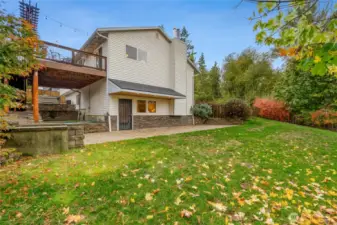 View of the home’s rear exterior highlighting the covered patio and extended stonework. Beautiful mix of privacy and open green space surrounded by colorful landscaping.