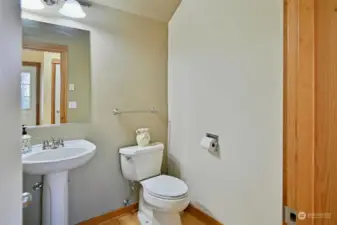 Powder room/half bath on the main floor with a pedestal sink and maple hardwood floors.