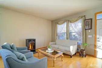 Living room with beautiful maple hardwood floors, gas stove for those cold NW nights, and a large window for natural lighting.