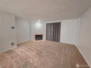 Living room with cBeing on the ground floor keeps this unit cool in the summer, and a wood burning fireplace is a nice option in fall & winter.ozy wood fireplace